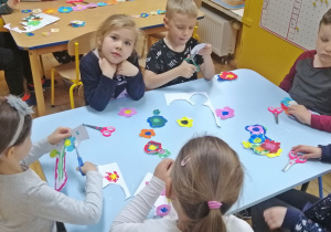 Dzieci namalowały farbami kwiaty i je wycinają